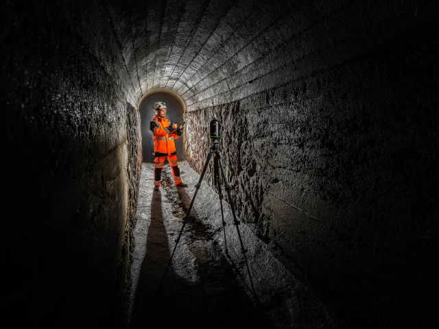 Opérateur réalisant un relevé 3D par scanner laser dans un ouvrage souterrain.