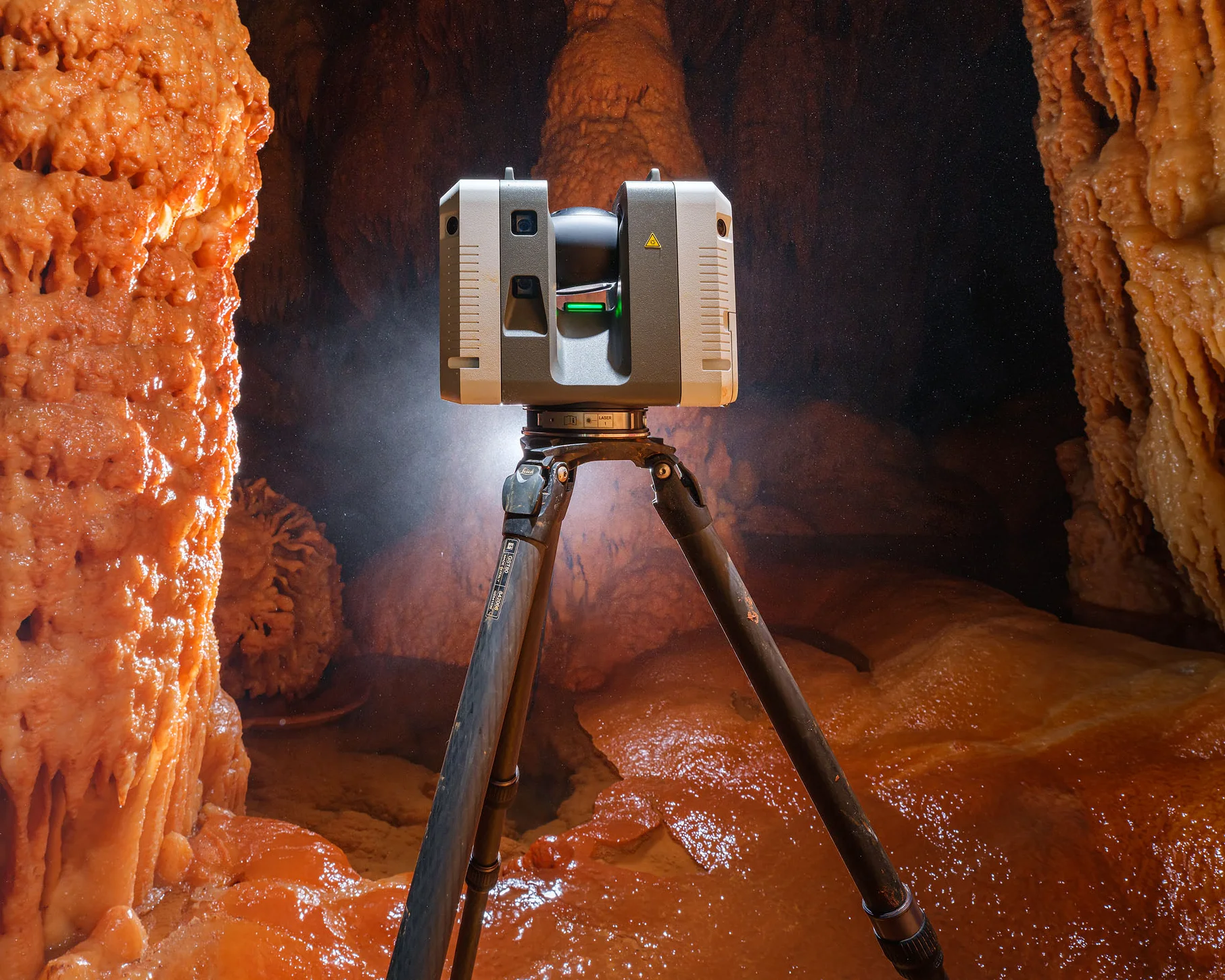 Scanner laser 3D sur trépied dans une grotte avec des stalactites et stalagmites.