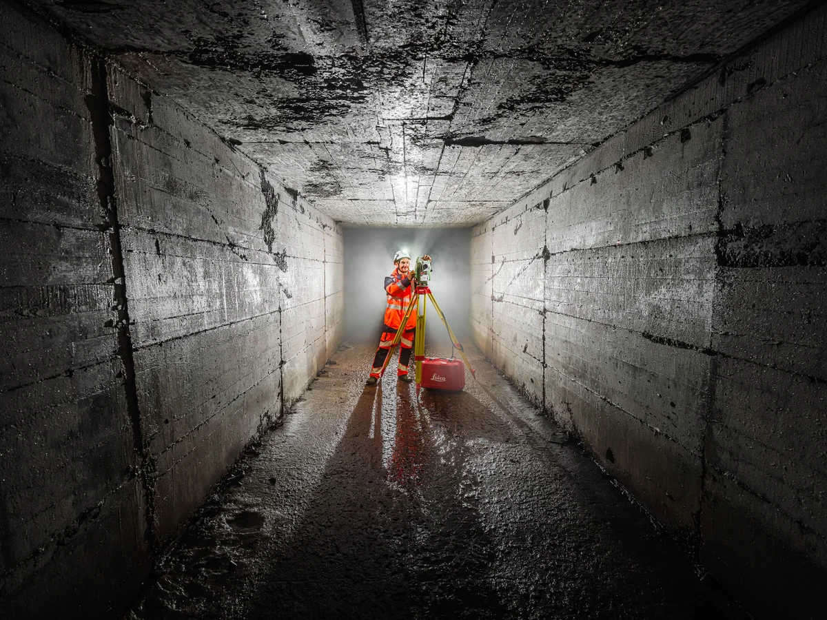 Opérateur dans un tunnel souterrain prenant des mesures avec un appareil de mesure laser.